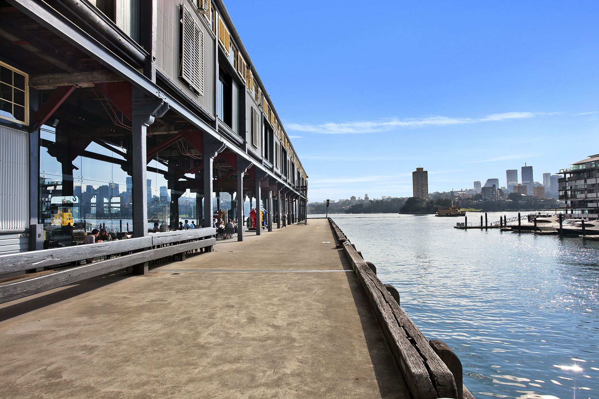 Diners along the pier apron at Piers 8&9 with the harbour and city skyline beyond