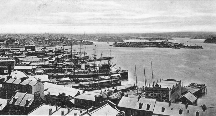 Historic photograph of ships berthed at the Walsh Bay wharves, seen over the rooftops of Millers Point